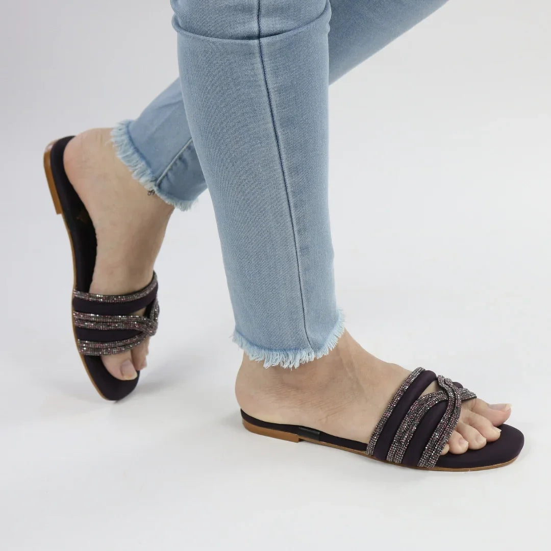 Purple sandals with glittery straps worn with light blue jeans on a white background.topmanshoes