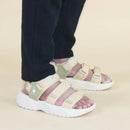 Beige sandals with white soles worn by a person on a beige background