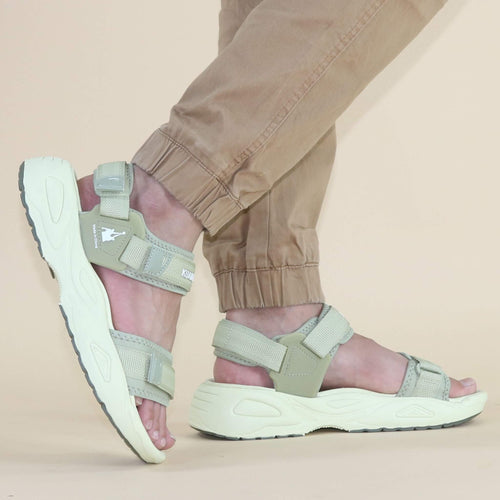 Beige sandals worn with beige pants on a beige background