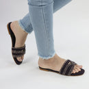 Purple sandals with glittery straps worn with light blue jeans on a white background.topmanshoes